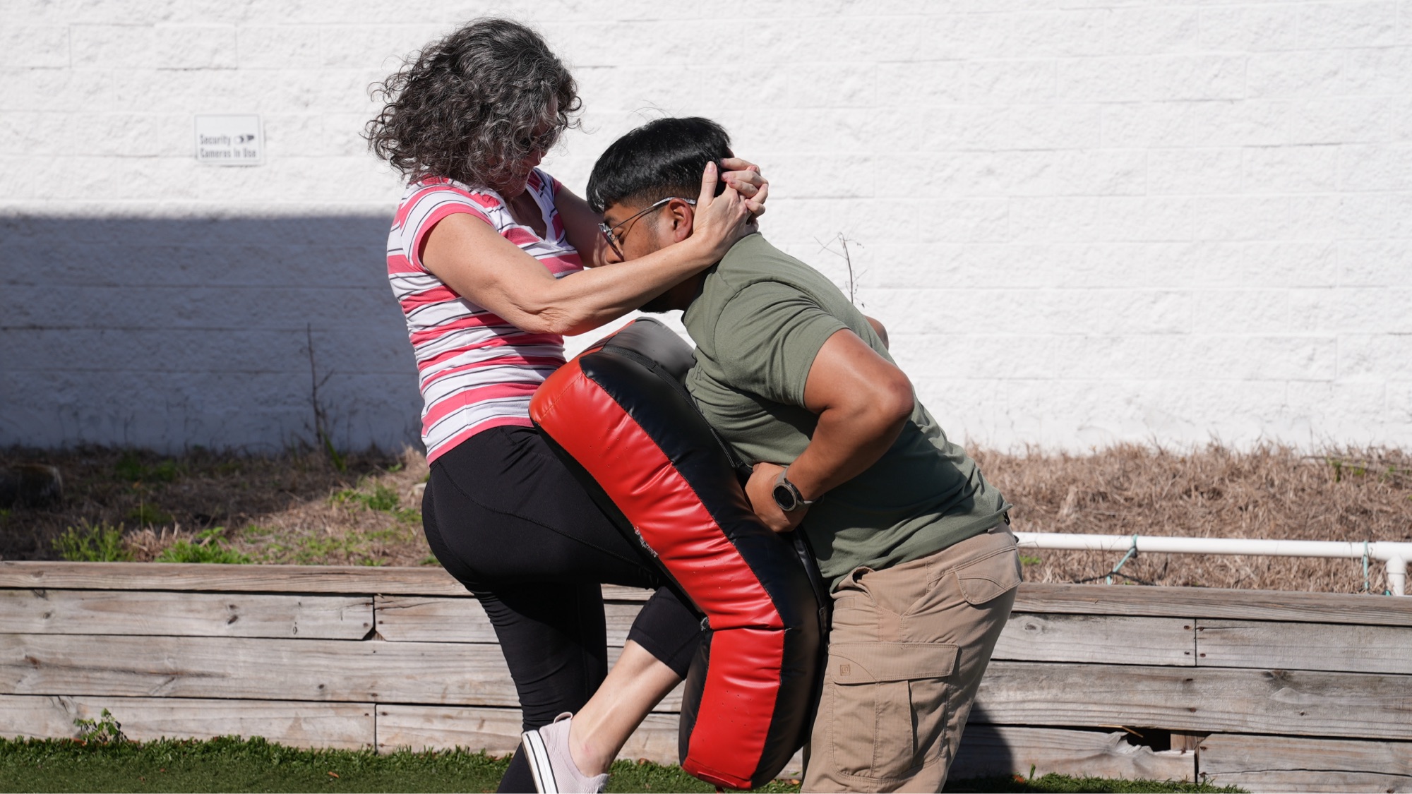 Student practicing a knee strike on a training pad during a self-defense class